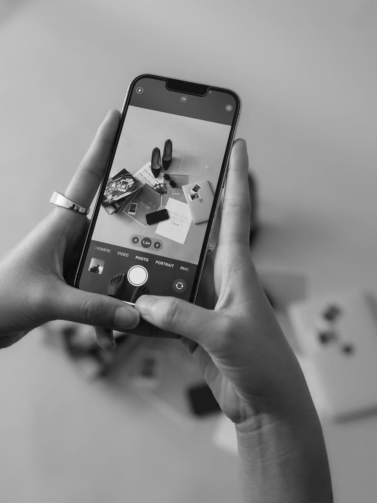 Black-and-white shot of hands framing event details on a phone camera