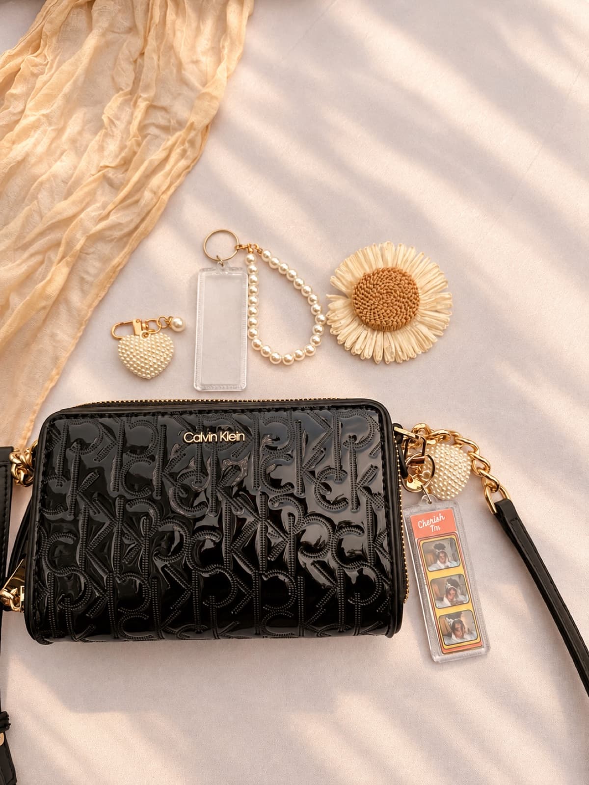 Photo-strip keychain with a pearl heart charm clipped to a black handbag