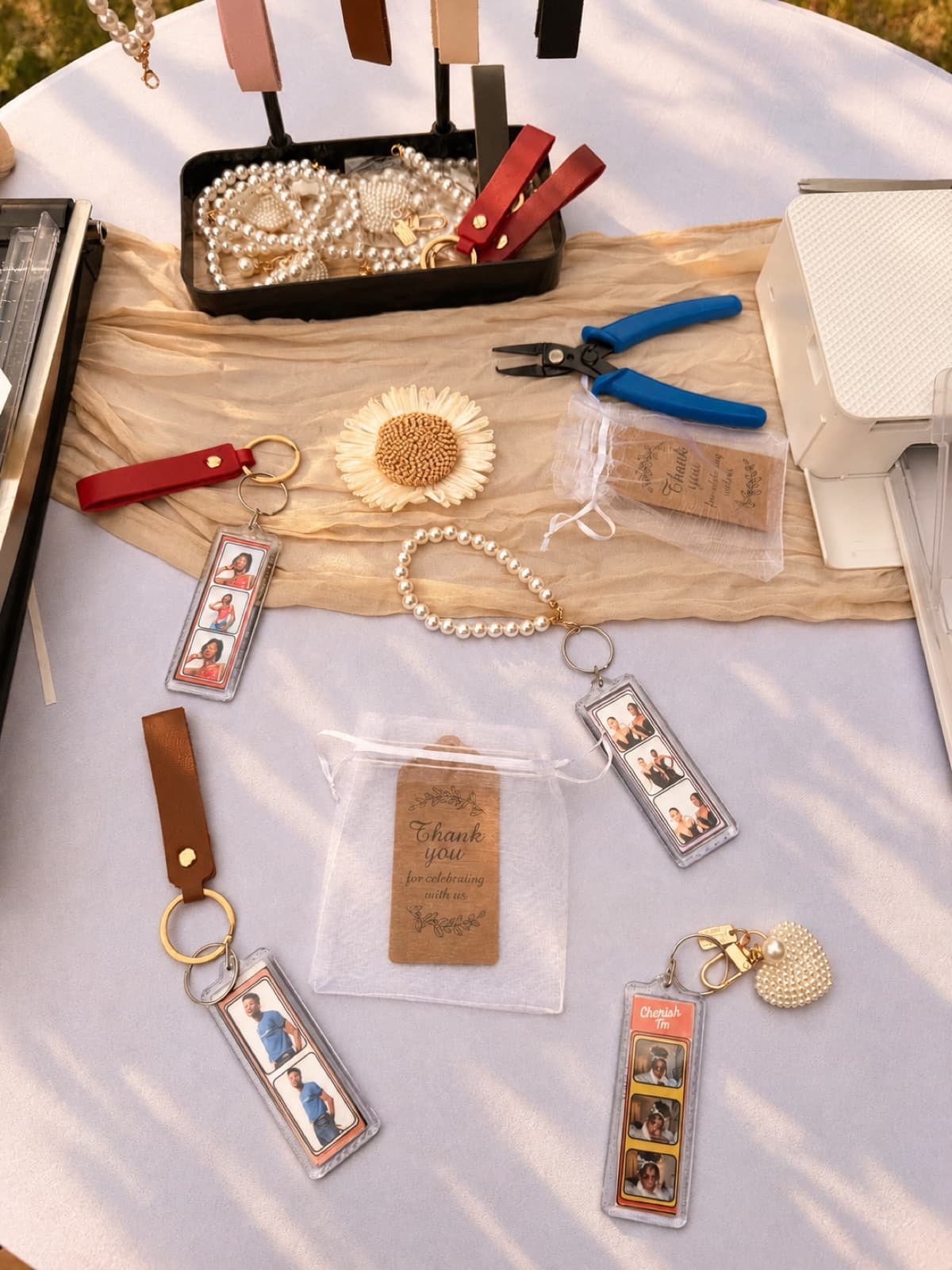 Keychain station table with finished photo-strip keychains, pearl straps, and thank-you favor bags