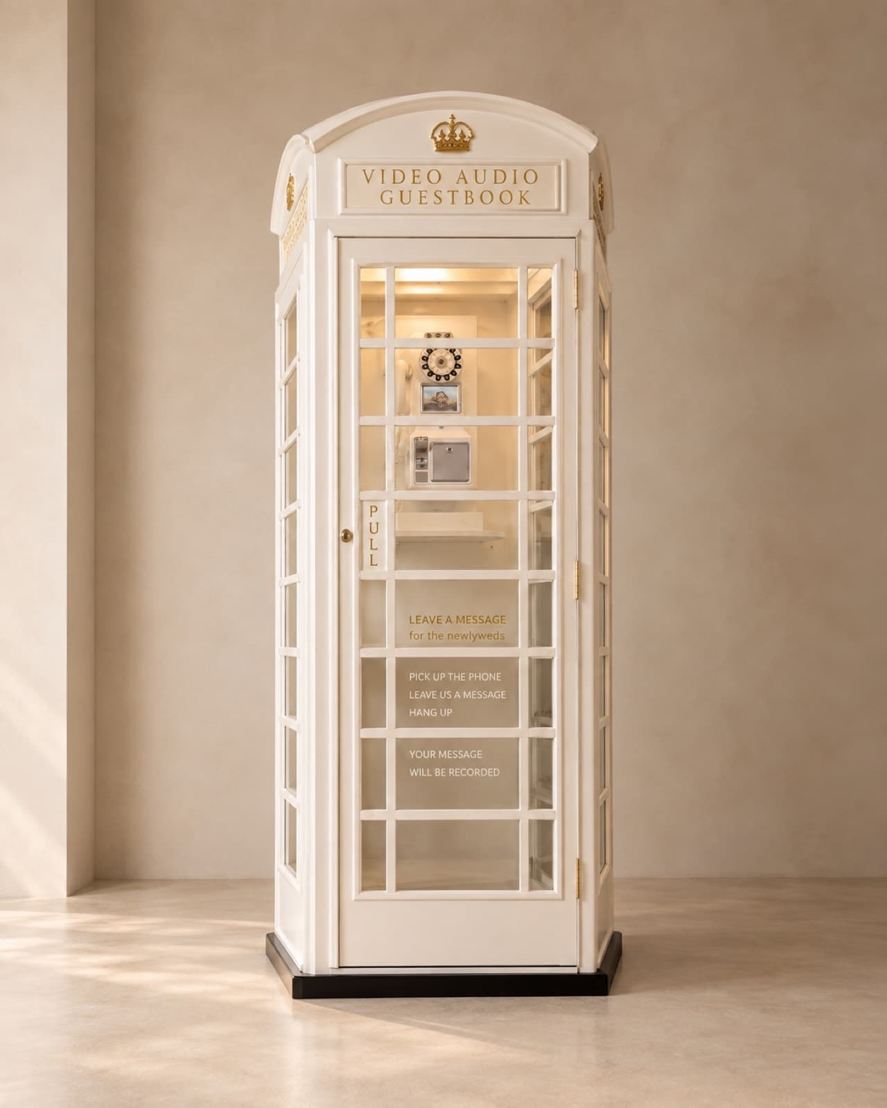 White vintage phone booth with a gold crown and 'Video Audio Guestbook' sign