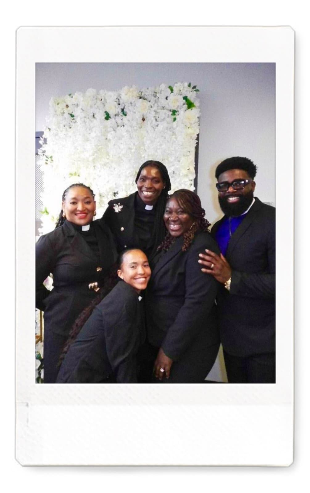 Instant photo of a group of five guests posing in front of a white flower wall