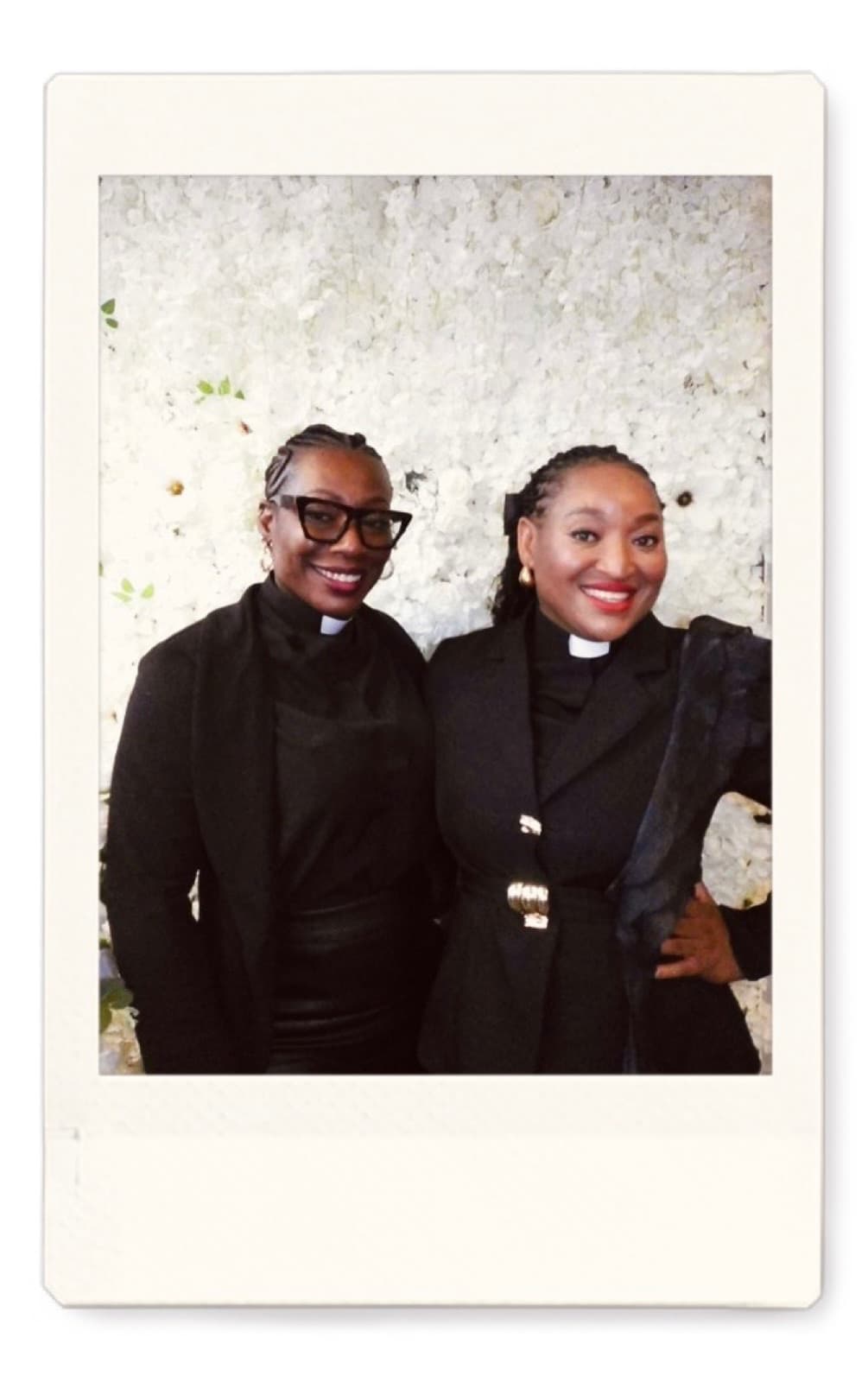 Instant photo of two smiling guests in front of a white flower wall