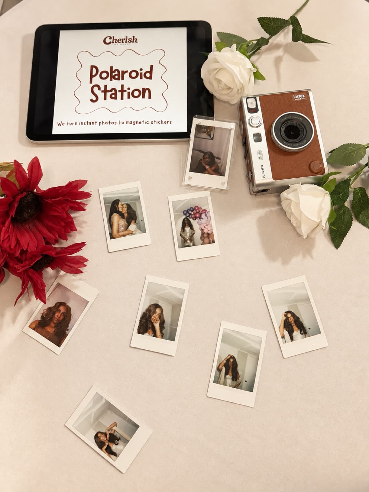Polaroid Station flat lay with instant prints, white roses, and red flowers